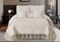 Quilted bedspread with lace trim on a bed in a bedroom setting
